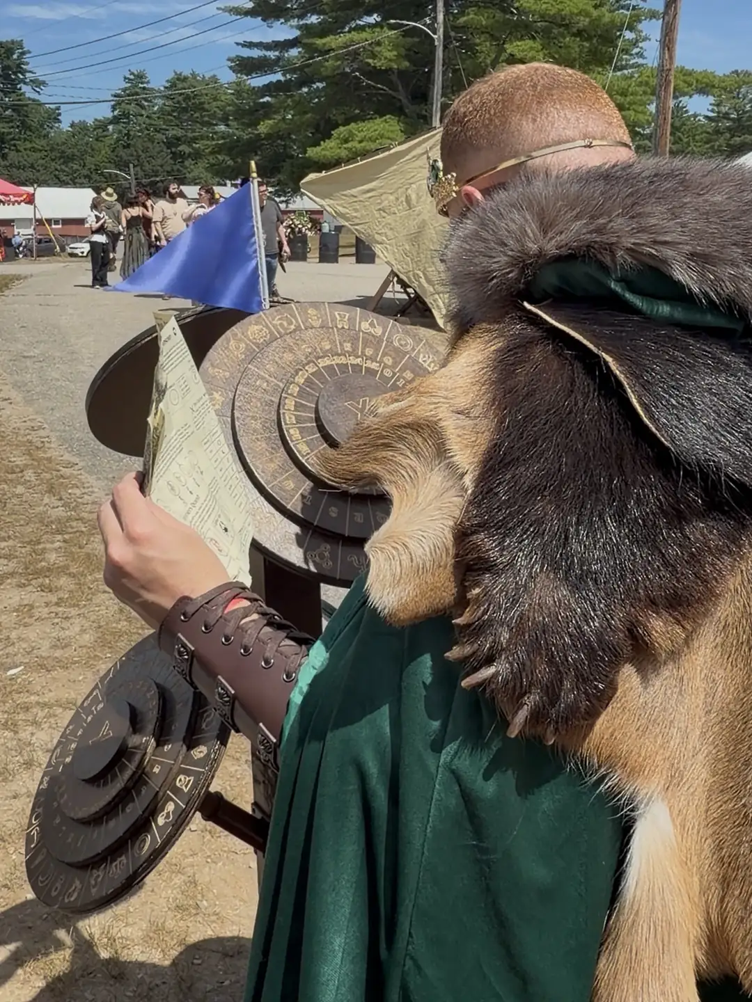 A player in a fur mantle holding up the quest sheet at the cipher wheels on the faire lane