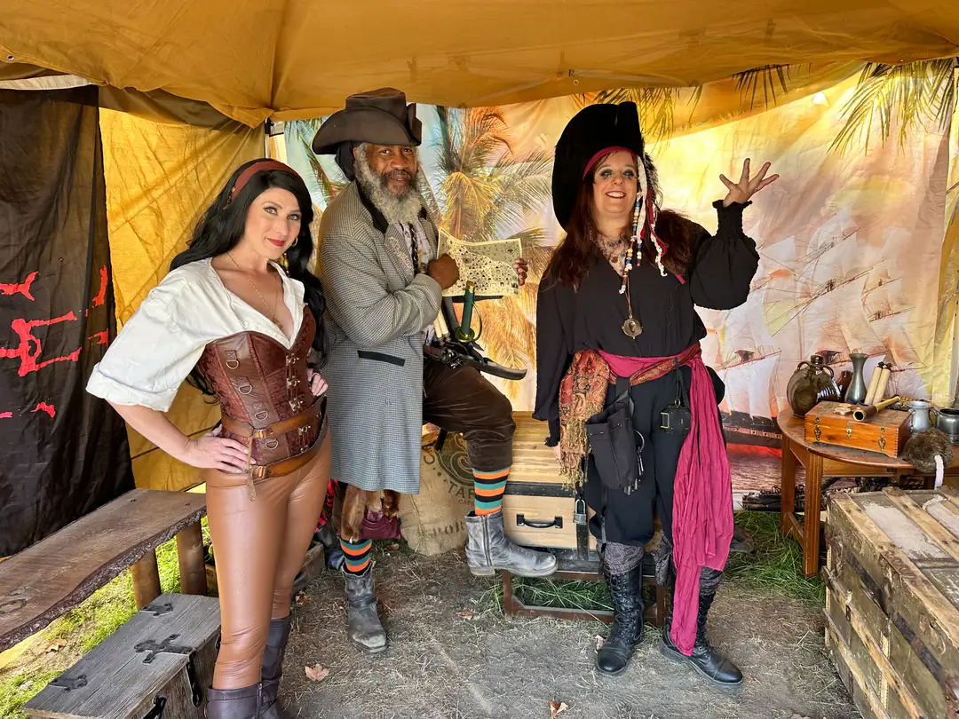 Three pirate crew members posing with a treasure map inside the tent