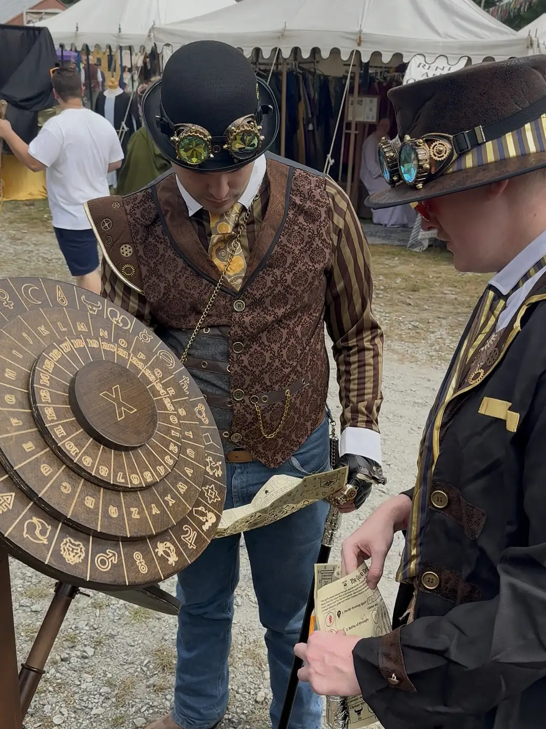 Two steampunk adventurers checking their quest sheets against the X cipher wheel