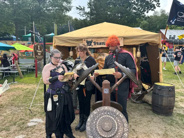 Three costumed adventurers studying quest papers near the cipher wheel