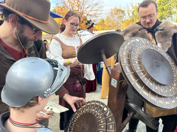 Group of costumed participants collaborating on a cipher puzzle with autumn foliage