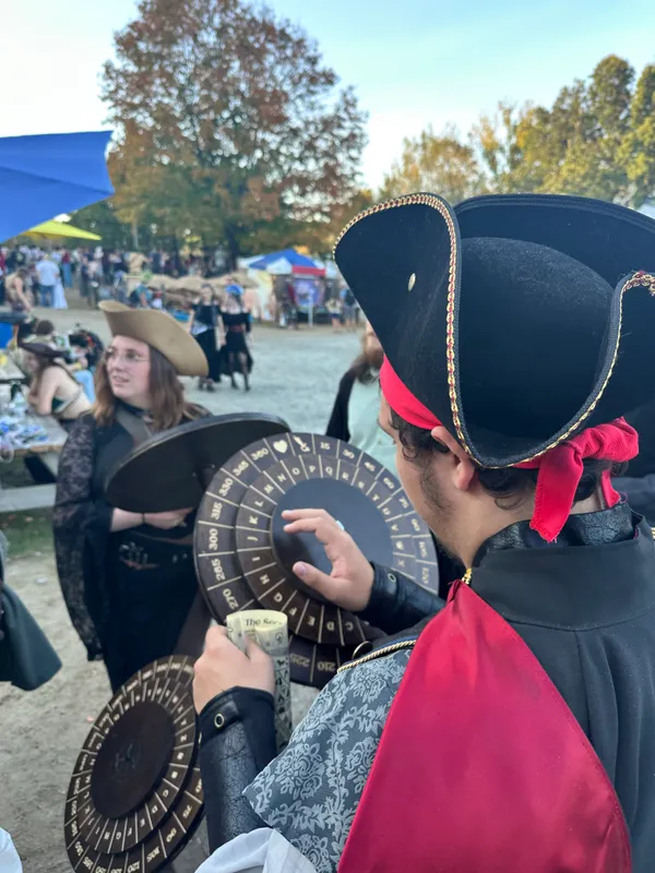 Participant in gold-trimmed tricorn hat spinning the cipher wheel decoder