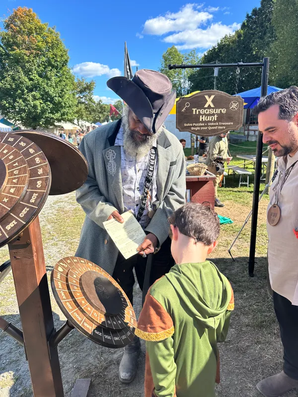 Pirate host showing a quest sheet to a young boy in a Robin Hood tunic